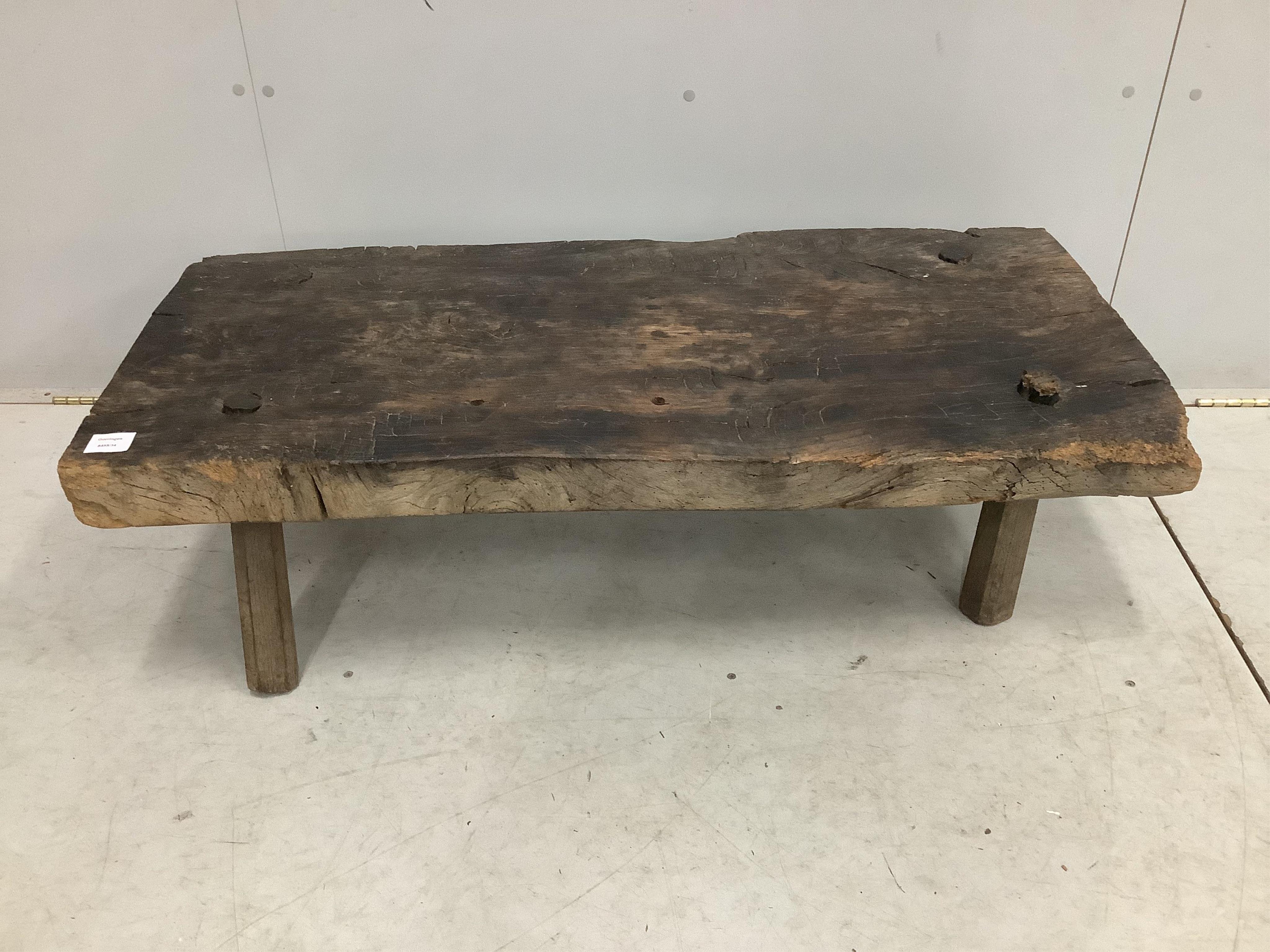 A Provincial rustic oak low table, on pegged supports, width 110cm, depth 50cm, height 33cm. Condition - poor to fair